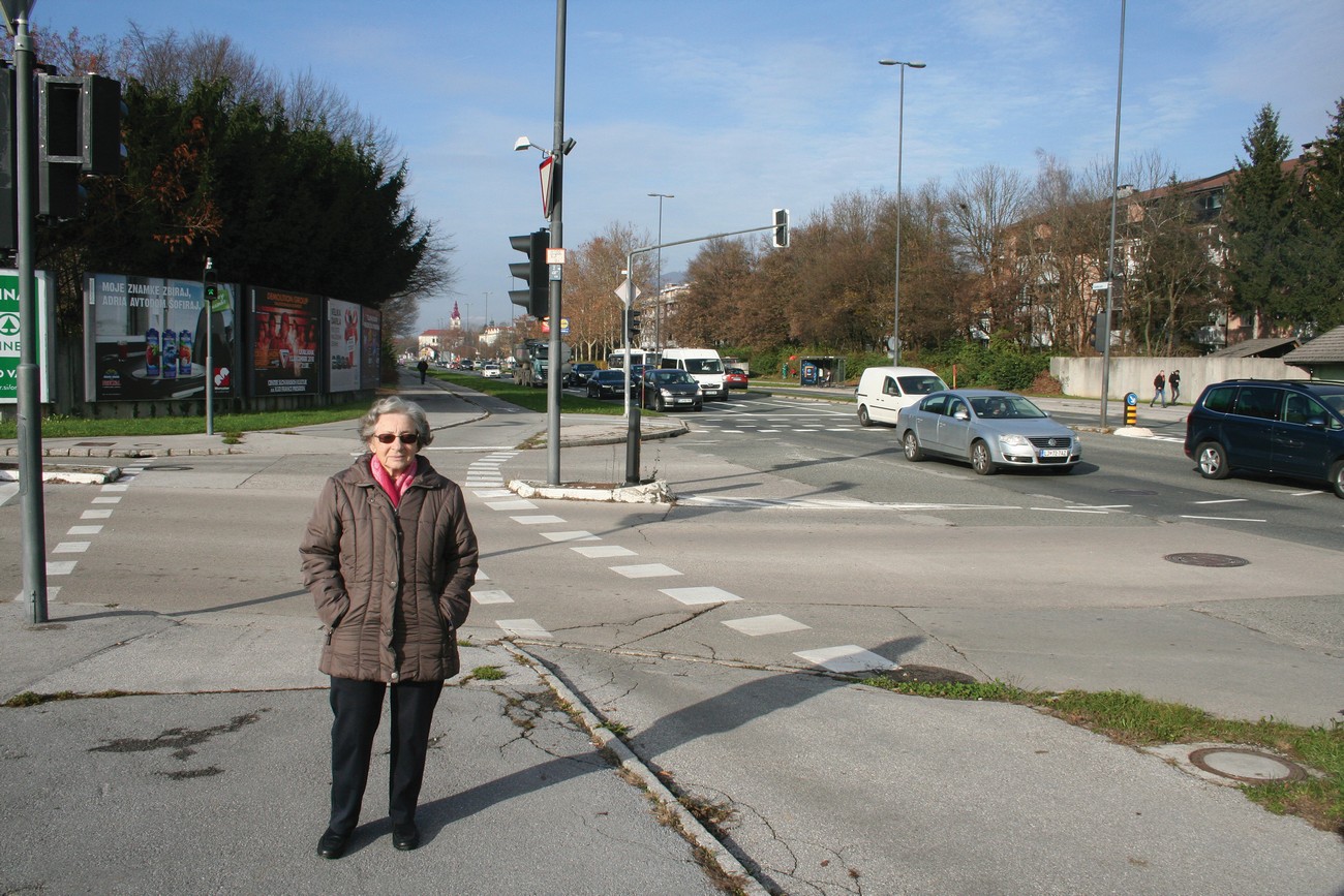 Vida Urgl (b. 1927) next to the junction of Cesta Andreja Bitenca and Celovška cesta in Ljubljana, where the border between Italy and Germany ran during World War II (border block at Šentvid). Vida smuggled herself across the wire of Ljubljana to the border between Italy and Germany at the border block in Šentvid. The guards wouldn't let her across even though she had relatives waiting for her on the German side with a pair of shoes. They had no choice but to toss the shoes over the wire. Ljubljana, 7 December 2018. Author: Božidar Flajšman.